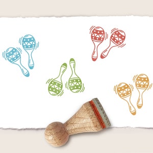 May include: A set of four wooden maracas with different coloured patterns. The maracas are on a white background with a wooden stamp handle.