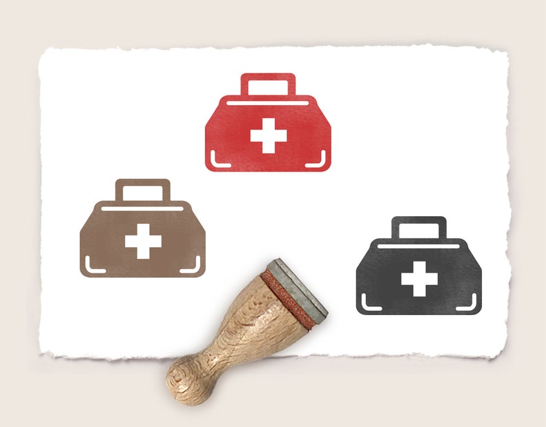 K&ouml;nnte beinhalten: Drei Stempel aus Gummi mit einem Erste-Hilfe-Kasten-Motiv. Die Stempel sind rot, braun und schwarz. Der Erste-Hilfe-Kasten hat ein wei&szlig;es Kreuz. Die Stempel befinden sich auf einem wei&szlig;en Blatt Papier mit einem rauen Rand.