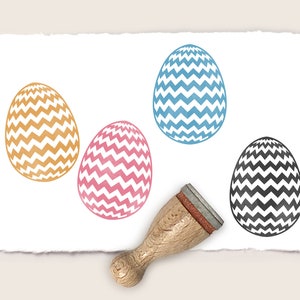 May include: Four rubber stamps with chevron patterns in blue, pink, orange, and black. The stamps are on a white background with a wooden handle.