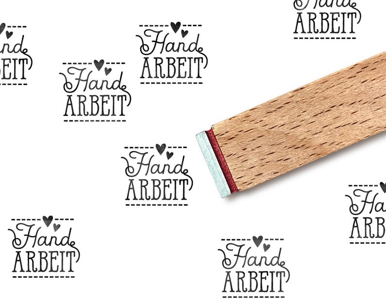 Pode incluir: Um carimbo de madeira com a palavra "Hand ARBEIT" em uma fonte decorativa, repetida em um fundo branco. O carimbo tem uma borda vermelha e prateada. A imagem sugere um tema artesanal ou feito &agrave; m&atilde;o.