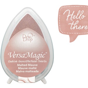May include: A pink VersaMagic chalk ink pad with the text "Malted Mauve" and "Dew Drop" in white. The ink pad is in a teardrop shape and is sitting on a white stand. A speech bubble with the text "Hello there" in white is in the background.