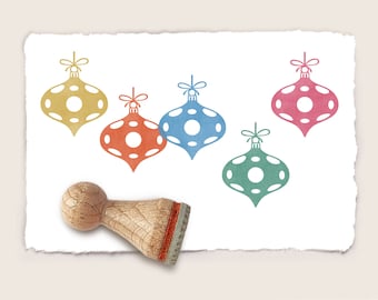 May include: Five Christmas ornament rubber stamps, each with a different color and pattern. The stamps are on a white piece of paper. A wooden stamp handle is also shown.
