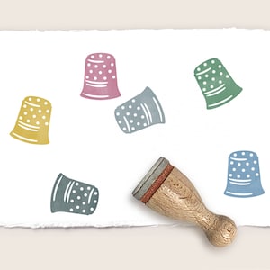 Könnte beinhalten: Sechs bunte Fingerhut-Stempel mit weißen Punkten auf weißem Hintergrund. Ein Stempelgriff aus Holz ist ebenfalls abgebildet.