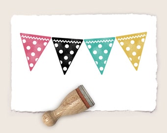 May include: Four colorful triangle-shaped flags with white polka dots. The flags are pink, black, teal, and yellow. The flags are hanging from a string. A wooden stamp is in the bottom right corner of the image.
