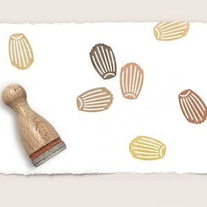 Puede incluir: Un conjunto de siete sellos de madera con diferentes colores y patrones de magdalenas. Los sellos están dispuestos sobre un fondo de papel blanco. También se incluye un mango de sello de madera en la imagen.