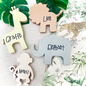 May include: Wooden animal cutouts in various colors, including a yellow giraffe, a brown lion, a gray elephant, a white monkey, and the words "Giraffe", "Lion", "Elephant", and "Monkey" written on each cutout.