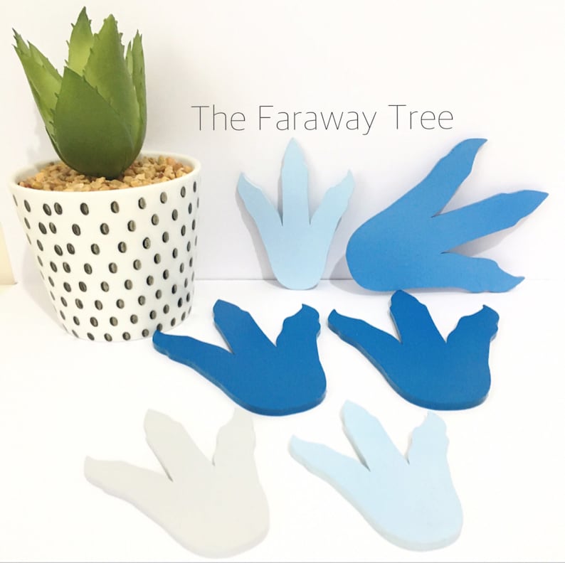 May include: Six blue and white dinosaur footprints, cut from paper or cardstock, with the text "The Faraway Tree" in black lettering.