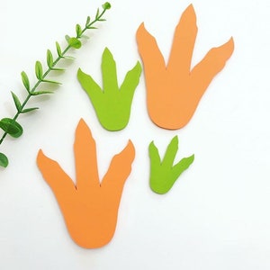 May include: Four dinosaur footprints cut out of paper. Two are orange and two are green.