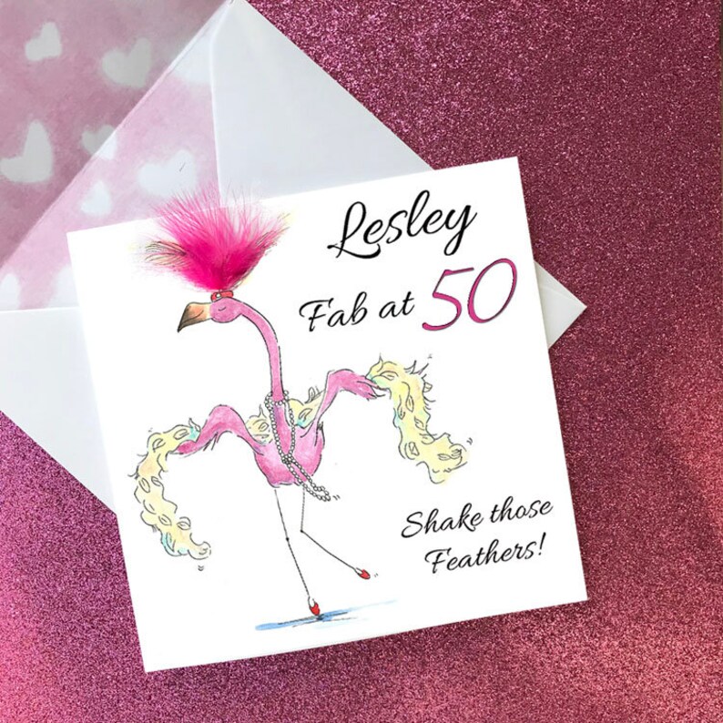 Puede incluir: Un flamenco rosa con un boa de plumas rosa y un collar de perlas, bailando con el texto "Lesley Fab at 50 Shake those Feathers!"