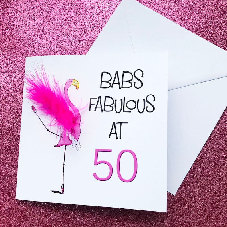 May include: A pink flamingo with a pink feather boa and a white tutu, with the text "BABS FABULOUS AT 50" on a white card.