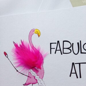 May include: A pink flamingo with a yellow beak and pink feathers is drawn on a white card. The flamingo is wearing a white tutu and has a pink feather on its head. The card says "Fabulous at 50".