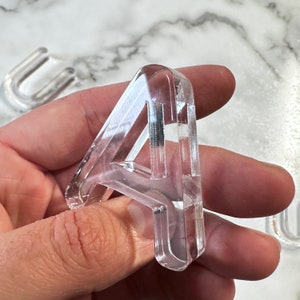 May include: A clear plastic number four, the number is thick and has a three-dimensional appearance.