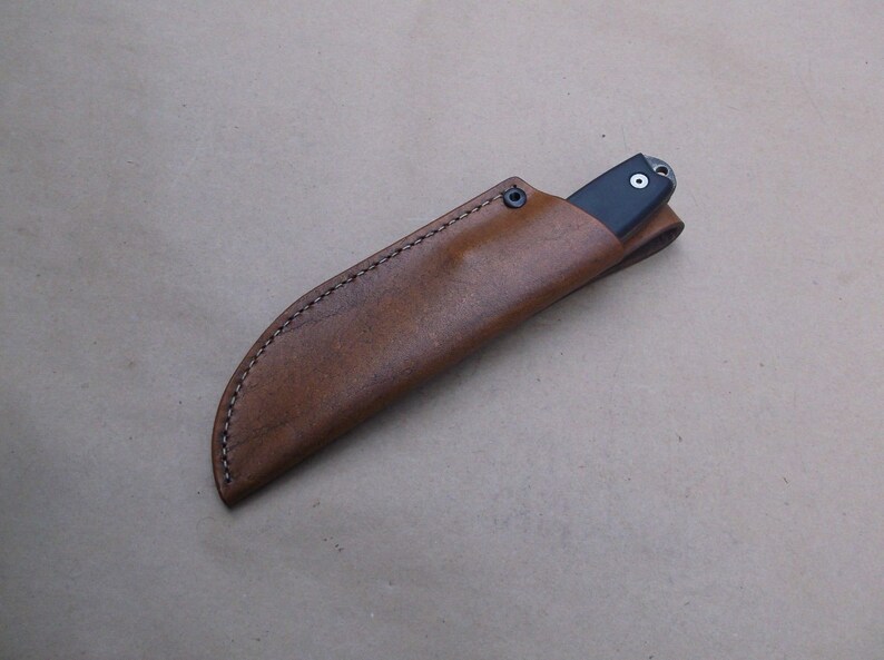 K&ouml;nnte beinhalten: Eine braune Lederscheide mit einem gen&auml;hten Rand f&uuml;r ein Messer.