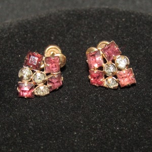 以下が含まれることがあります： ピンクとクリアなラインストーンが付いたゴールドトーンのイヤリングのペア。イヤリングは石のクラスターの形をしています。