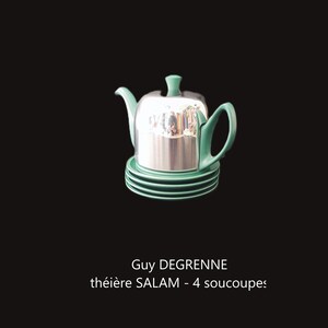 Puede incluir: Una tetera plateada con asa, boquilla y tapa verdes, sobre una pila de cuatro platillos verdes. La tetera tiene una superficie reflectante. El texto "Guy DEGRENNE théière SALAM - 4 soucoupes" está debajo.