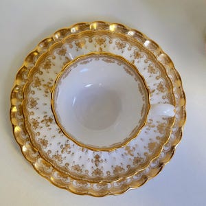 Spode Fleur de Lys Trio ~ Xícara e pires planos, prato de sobremesa ~ Osso, Fleur de Lys dourado, acabamento dourado ~ Conjunto de três peças feito na Inglaterra