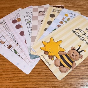 May include: A selection of illustrated cards with different designs. One card shows a sun and a bear in a bee costume, with the text "my jellycat collection." Other cards feature numbers, dots, and animal illustrations.