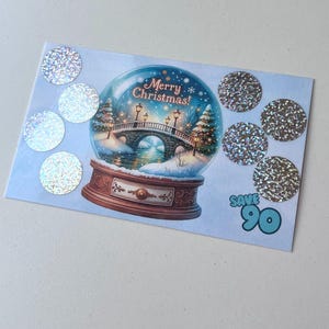 May include: A blue and white Christmas card with a snow globe illustration and the text "Merry Christmas!"  The card has eight silver holographic stickers on it. The text "Save 90" is printed in blue on the card.