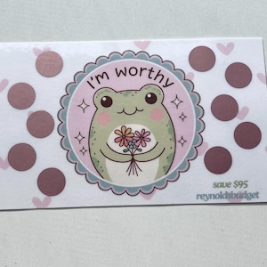 May include: A white card with pink hearts and brown dots. A green frog with pink cheeks holds a bouquet of flowers. The card says "I'm worthy" and "save $95 reynoldsbudget".