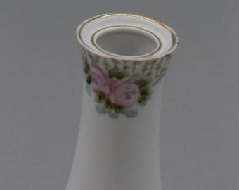 May include: White ceramic vase with a gold rim and floral designs. The vase has a flared base and a narrow neck. The floral designs are pink roses with green leaves and blue accents.
