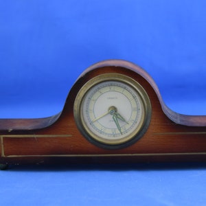May include: A vintage wooden clock with a white face and black hands. The clock is in a brown wooden case with a gold trim.