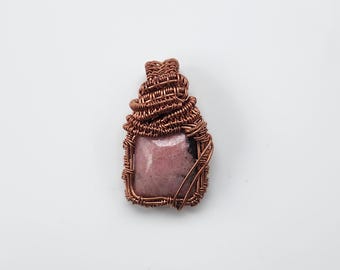 May include: A copper wire wrapped pendant featuring a pink and black square-shaped gemstone.