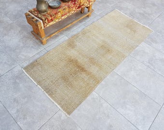May include: A light beige rectangular rug with a subtle woven texture. The rug is laid out on a tiled floor.