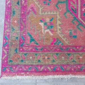 May include: A pink and teal patterned rug with a fringed edge. The rug has a traditional design with geometric shapes and floral motifs.