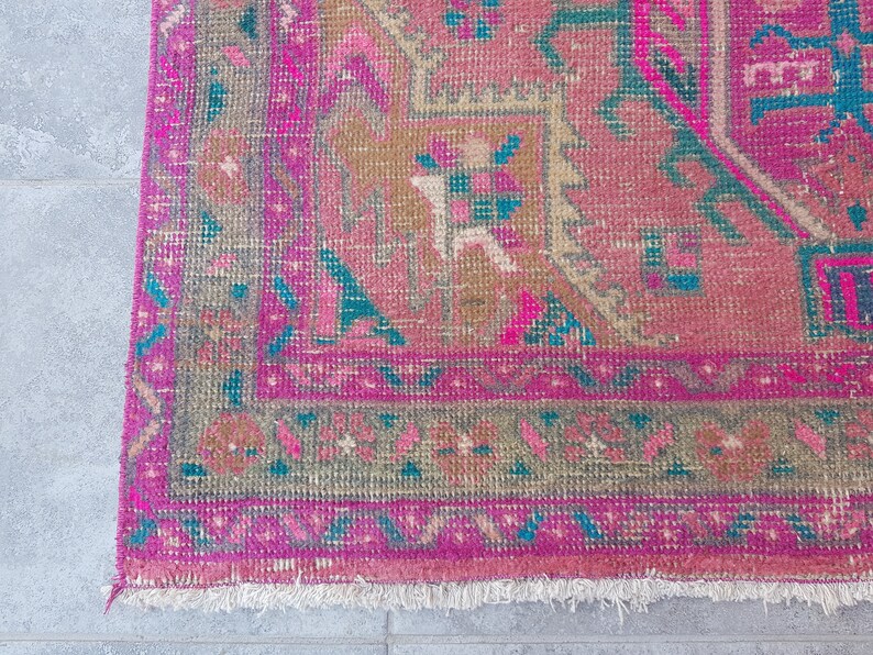 May include: A pink and teal patterned rug with a fringed edge. The rug has a traditional design with geometric shapes and floral motifs.