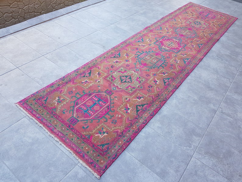 May include: A pink and brown patterned runner rug with a fringed edge. The rug has a traditional design with geometric shapes and floral motifs.