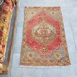 May include: A red, beige, and brown patterned rug with a fringe border. The rug has a diamond-shaped design in the center.