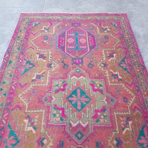 May include: A pink and green vintage rug with a traditional Persian design. The rug has a central medallion and intricate floral patterns.