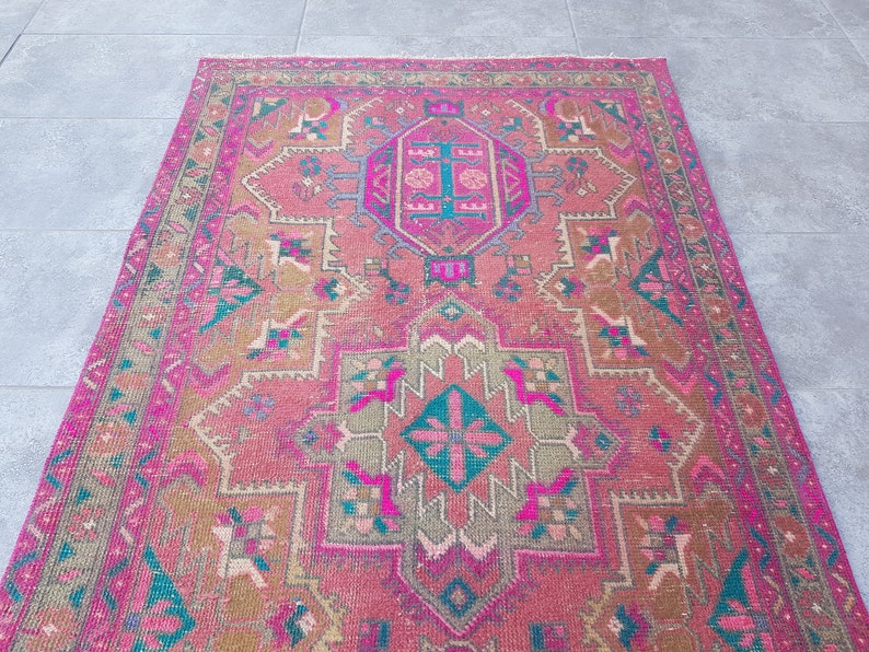 May include: A pink and green vintage rug with a traditional Persian design. The rug has a central medallion and intricate floral patterns.