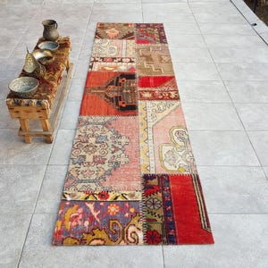 May include: A colourful patchwork runner rug with a variety of patterns and colours, including red, blue, green, and beige. The rug is made of different pieces of fabric sewn together.