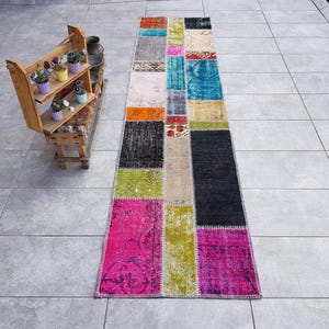 Pode incluir: Um tapete corredor de patchwork colorido com uma variedade de cores e padrões, incluindo rosa, verde, azul e preto. O tapete é feito de materiais reciclados e é perfeito para adicionar um toque de estilo boêmio a qualquer cômodo.