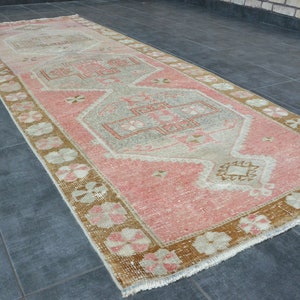 May include: A vintage runner rug with a pink and beige color scheme. The rug has a traditional floral pattern with a central medallion.