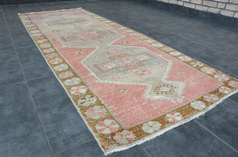 May include: A vintage runner rug with a pink and beige color scheme. The rug has a traditional floral pattern with a central medallion.