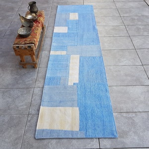 May include: A blue and white geometric patterned runner rug. The rug has a modern design with a patchwork look.