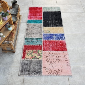 Può includere: Un tappeto patchwork colorato con una varietà di motivi e colori, tra cui rosso, blu, verde e rosa. Il tappeto è realizzato con materiali riciclati e ha un aspetto unico e fatto a mano.