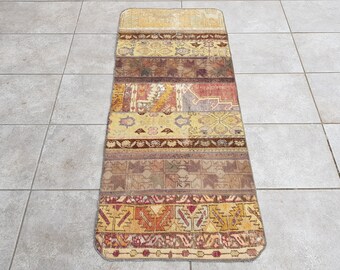 May include: A long, rectangular rug with a patchwork design. The rug is made of different colored fabrics, including red, brown, yellow, and beige. The rug has a fringe border.