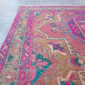 May include: A pink and brown patterned rug with a traditional design. The rug has a faded look and is made of woven fibers.