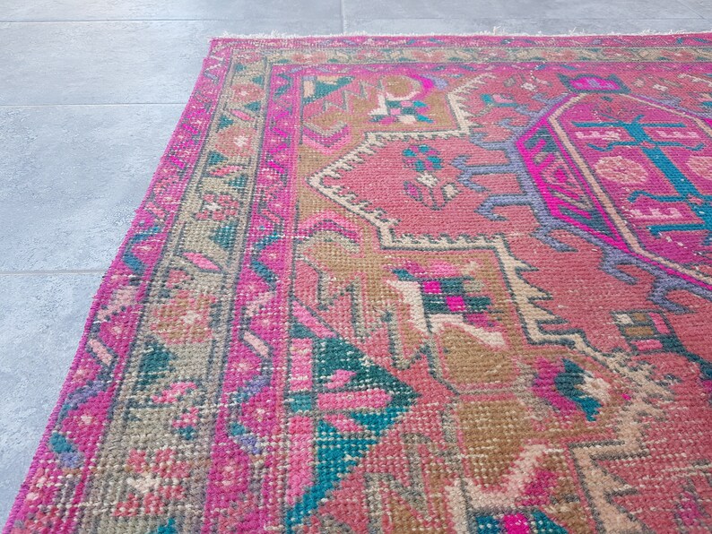 May include: A pink and brown patterned rug with a traditional design. The rug has a faded look and is made of woven fibers.