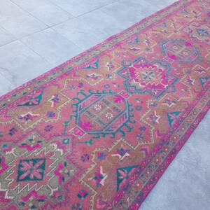 May include: A pink and teal patterned rug with intricate designs. The rug has a faded, vintage look and is perfect for adding a touch of bohemian style to any room.