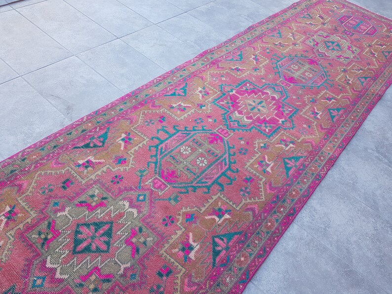 May include: A pink and teal patterned rug with intricate designs. The rug has a faded, vintage look and is perfect for adding a touch of bohemian style to any room.