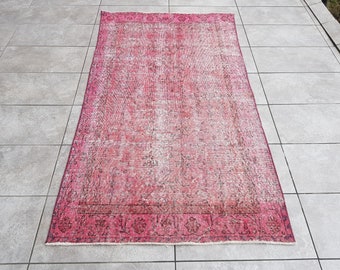 May include: A vintage pink and white rug with a floral pattern. The rug has a faded look and a worn border.