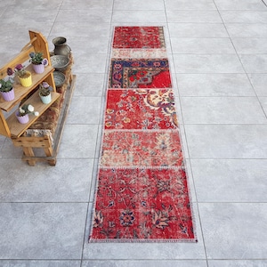 以下が含まれることがあります： 花柄の赤い長方形の敷物。パッチワークで、異なる布地を縫い合わせて作られています。