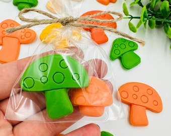 May include: A clear plastic bag filled with small, colorful mushroom-shaped soaps. The bag is tied with twine and there are several loose mushroom soaps scattered around the bag.
