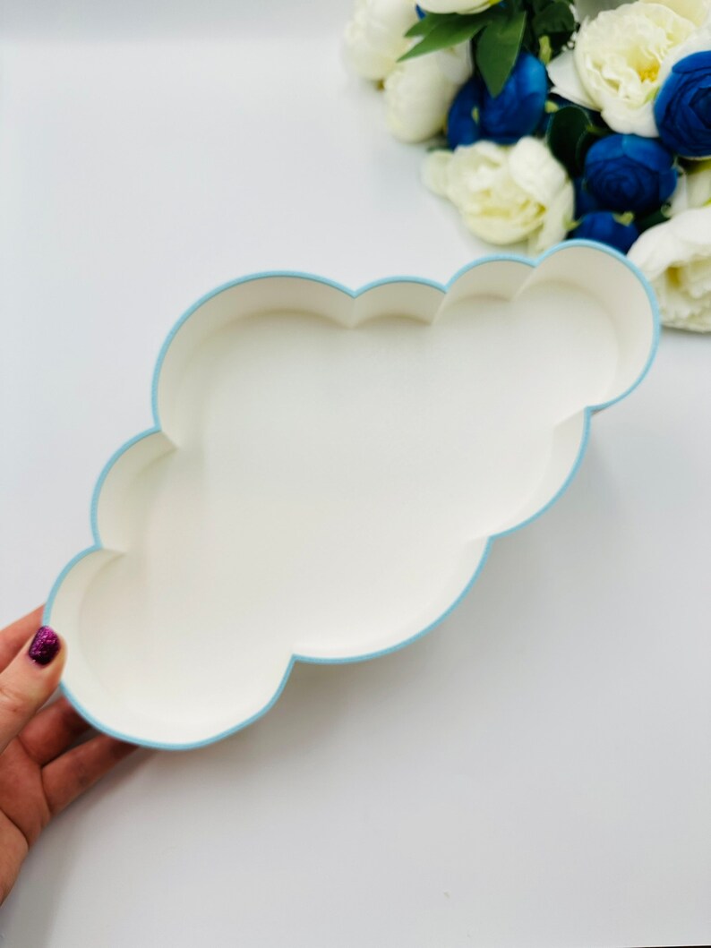 May include: A white cloud-shaped tray with a light blue border. The tray is made of paper and is perfect for holding small items.