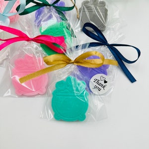 Puede incluir: Surtido de pequeños favores de jabón coloridos con forma de despertador. Cada jabón está envuelto en celofán transparente con una cinta y una etiqueta que dice "Gracias".