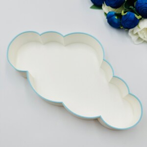May include: A white cloud-shaped tray with a light blue border. The tray is empty and is sitting on a white surface.